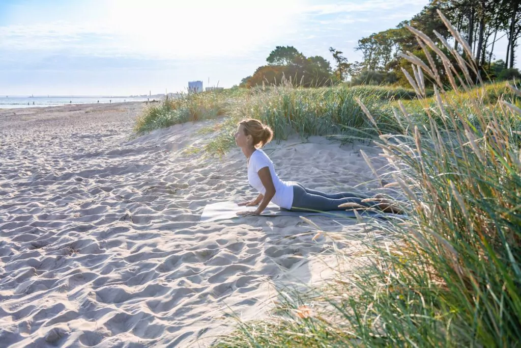 Yoga am Strand hilft dabei, Stress und Belastungen hinter sich zu lassen und wieder ganz bei sich anzukommen. Foto: Tourismusverband Mecklenburg-Vorpommern/Tiemann